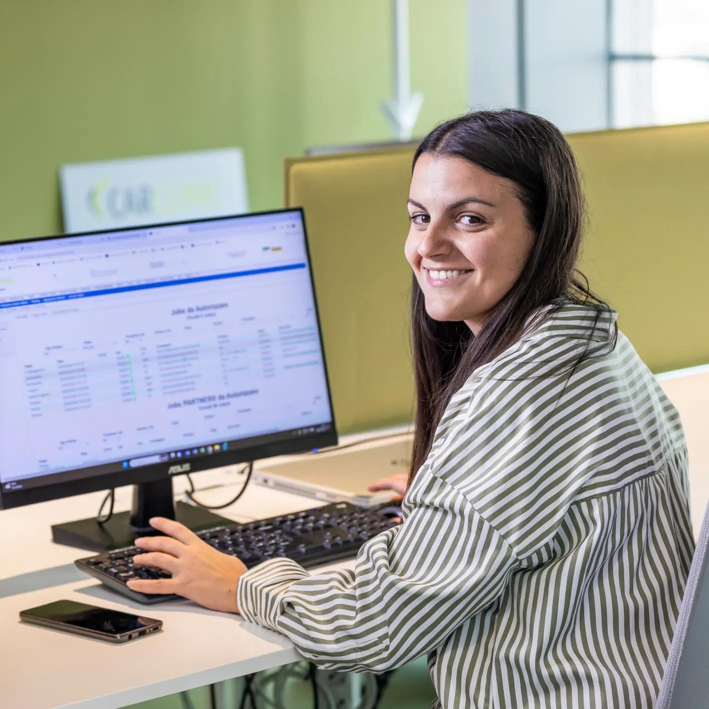 Dipendente Car Clinic sorride mentre lavora al computer