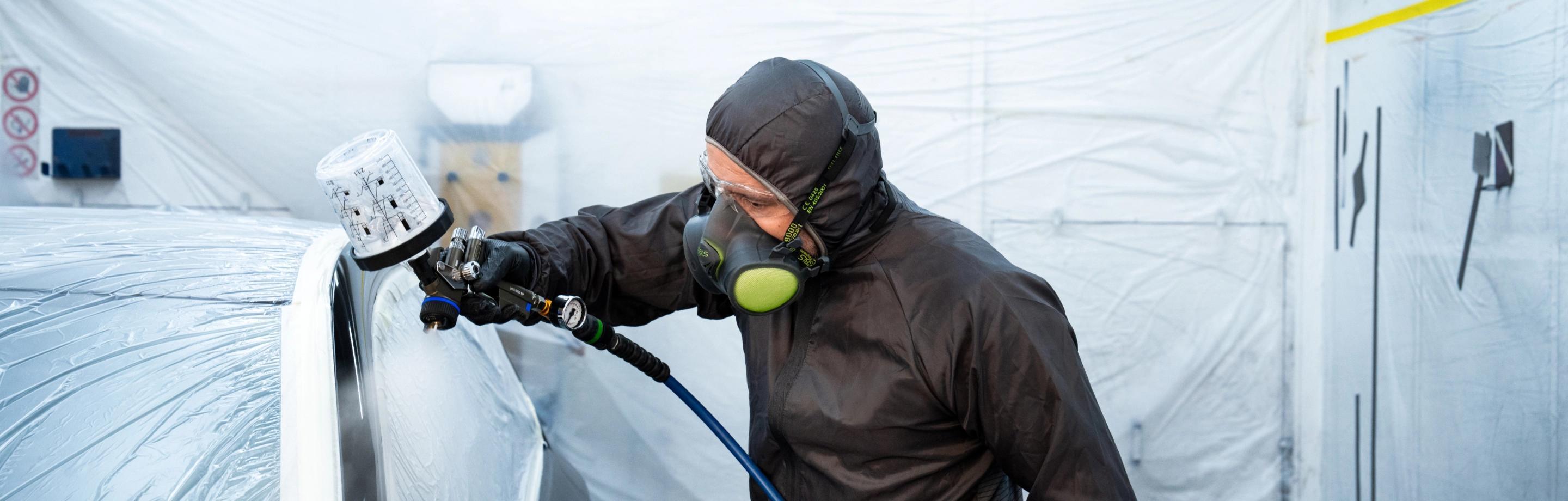 Tecnico al lavoro per riparare la verniciatura di un auto