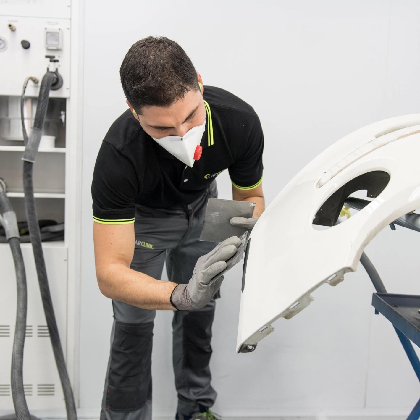 Carrozziere stucca parte di carrozzeria ammalorata