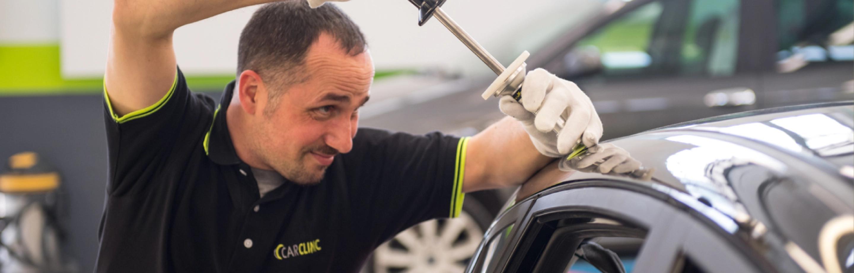 Carrozziere al lavoro durante la riparazione di una carrozzeria