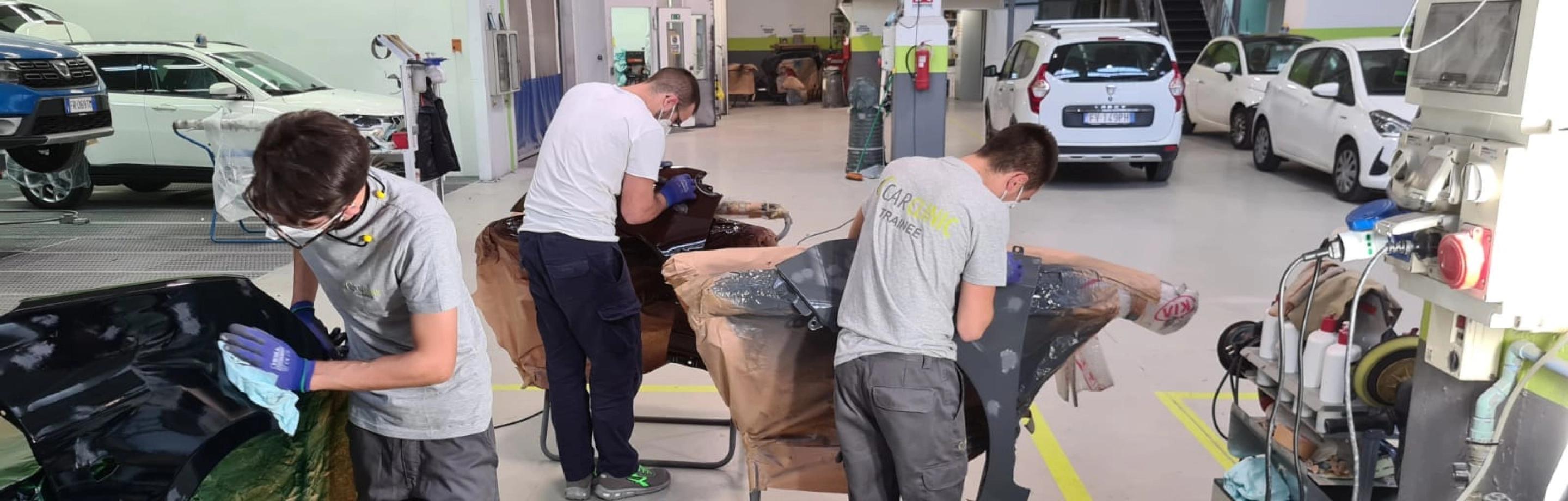 Team di carrozzieri a lavoro in carrozzeria