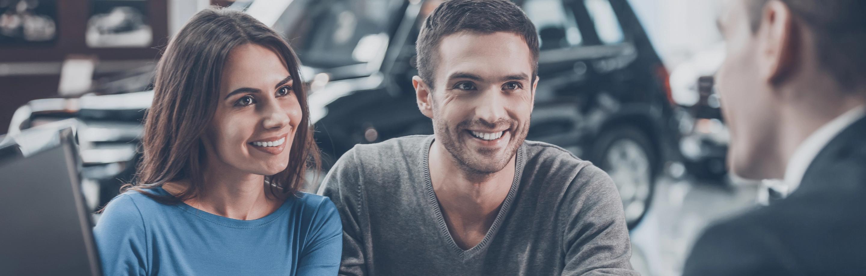 Coppia di clienti che parlano con il proprio agente assicurativo. Le loro espressioni esprimono serenità e fiducia.